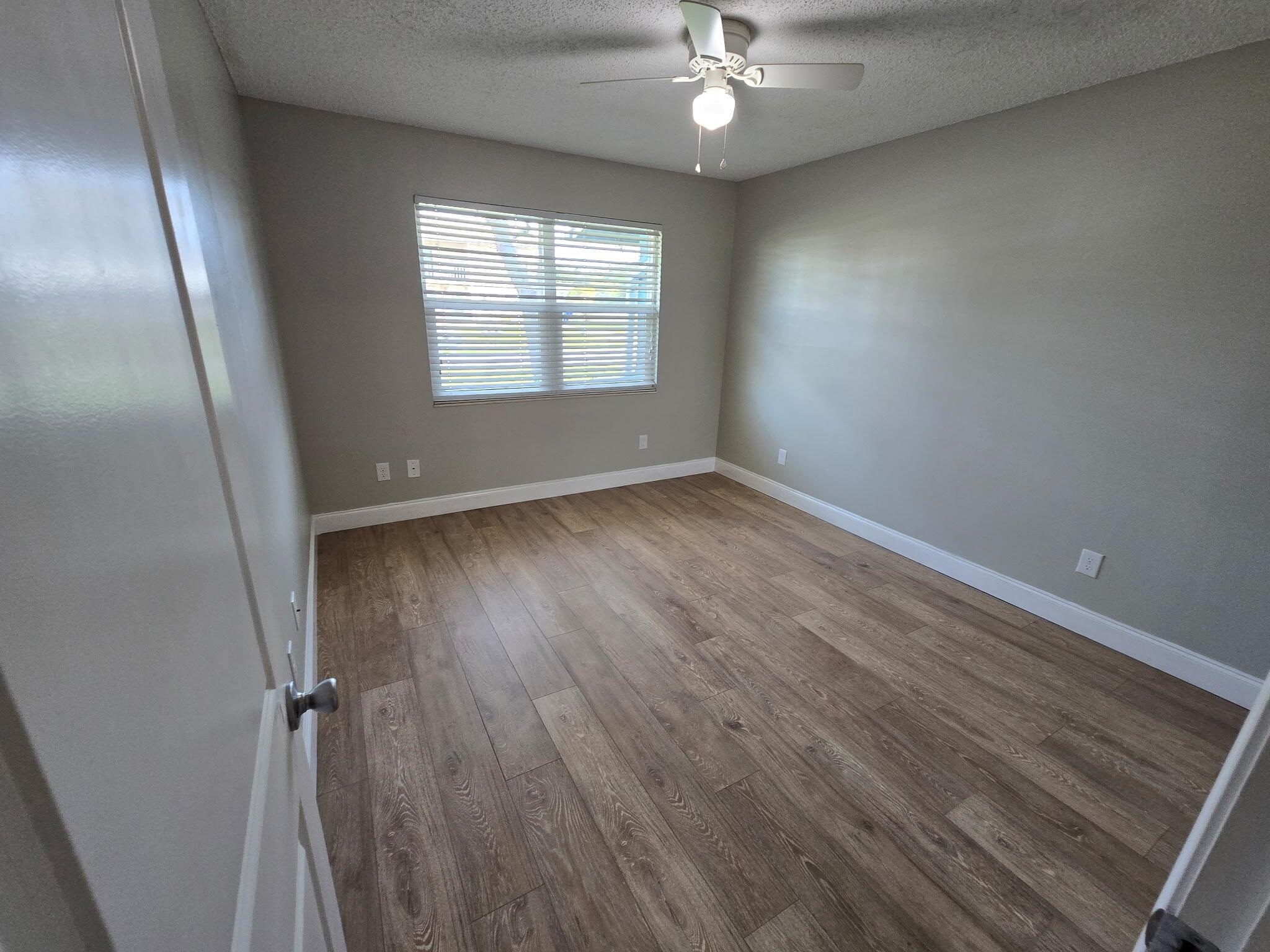 125 Rio Del Mar Street, Unit B St. Augustine, FL 32080 - Photo 11 of 17 Empty room featuring dark wood-type flooring, a textured ceiling, and a ceiling fan