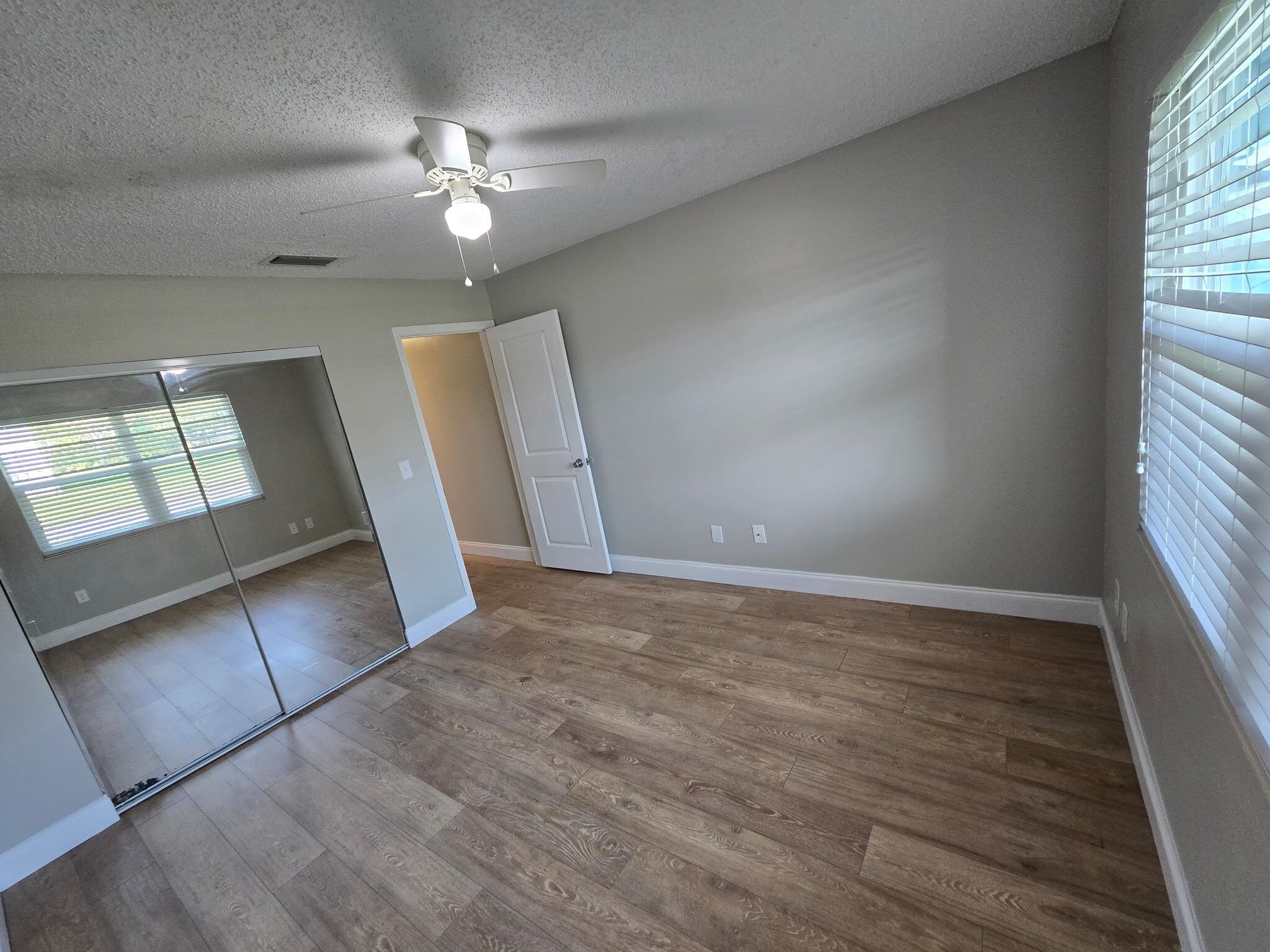 125 Rio Del Mar Street, Unit B St. Augustine, FL 32080 - Photo 12 of 17 Unfurnished bedroom with a closet, a textured ceiling, a ceiling fan, and dark wood finished floors