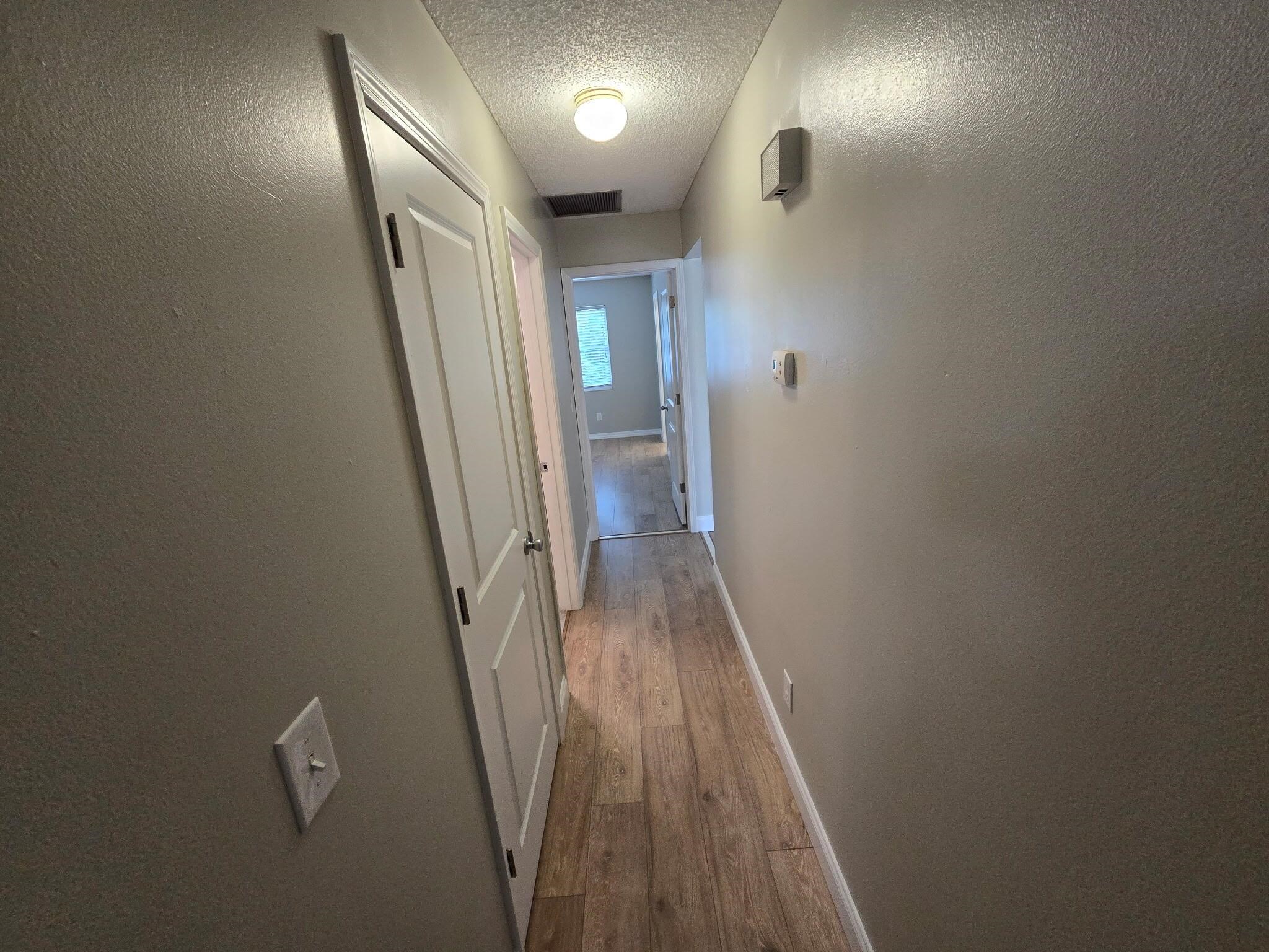 125 Rio Del Mar Street, Unit B St. Augustine, FL 32080 - Photo 14 of 17 Hall with a textured ceiling, dark wood-style flooring, and a textured wall