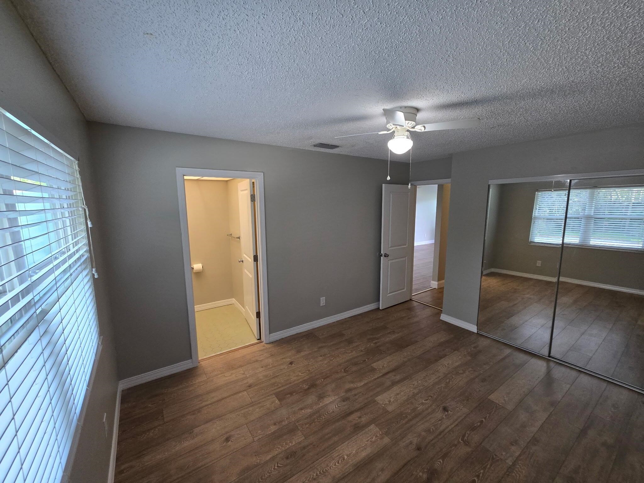125 Rio Del Mar Street, Unit B St. Augustine, FL 32080 - Photo 15 of 17 Unfurnished bedroom featuring dark wood-style floors, ceiling fan, a textured ceiling, a closet, and connected bathroom