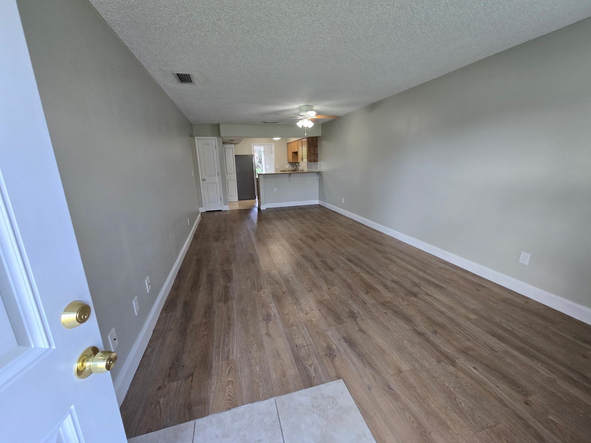 125 Rio Del Mar Street, Unit B St. Augustine, FL 32080 - Photo 5 of 17 Unfurnished living room featuring dark wood-type flooring, a textured ceiling, and ceiling fan