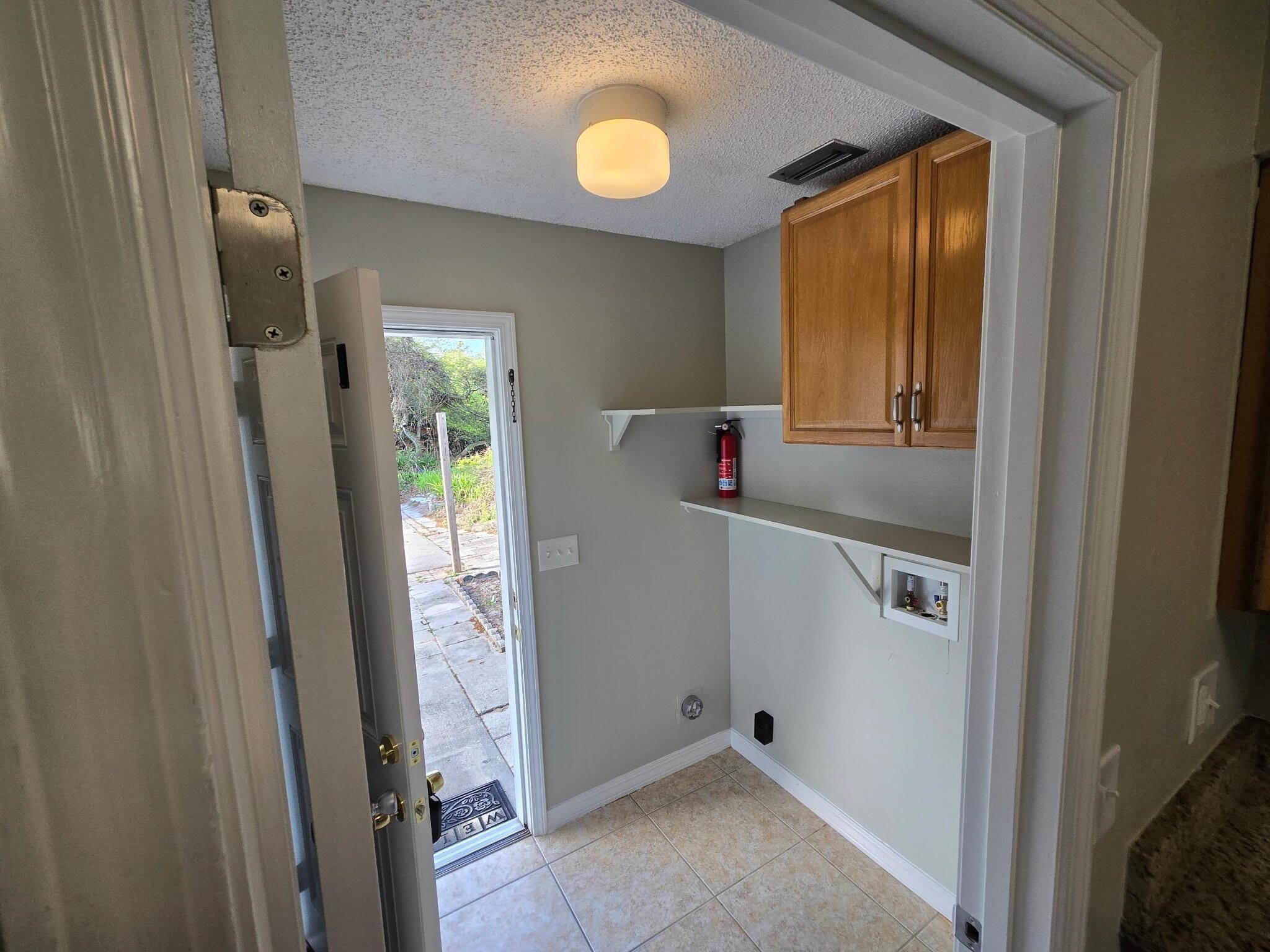 125 Rio Del Mar Street, Unit B St. Augustine, FL 32080 - Photo 7 of 17 Laundry room featuring a textured ceiling, hookup for a washing machine, cabinet space, and light tile patterned floors