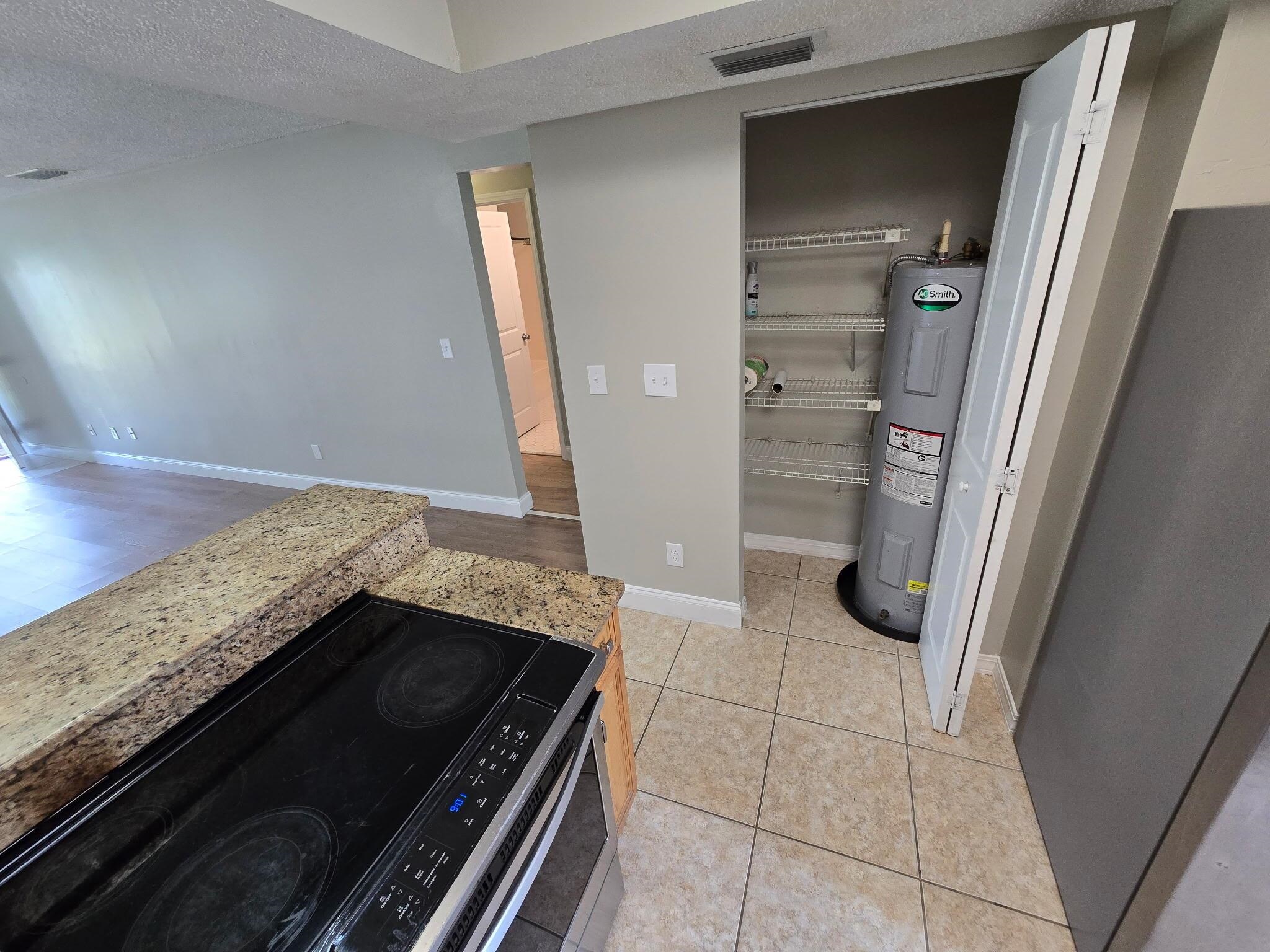 125 Rio Del Mar Street, Unit B St. Augustine, FL 32080 - Photo 8 of 17 Kitchen with electric stove, a textured ceiling, water heater, and light tile patterned flooring