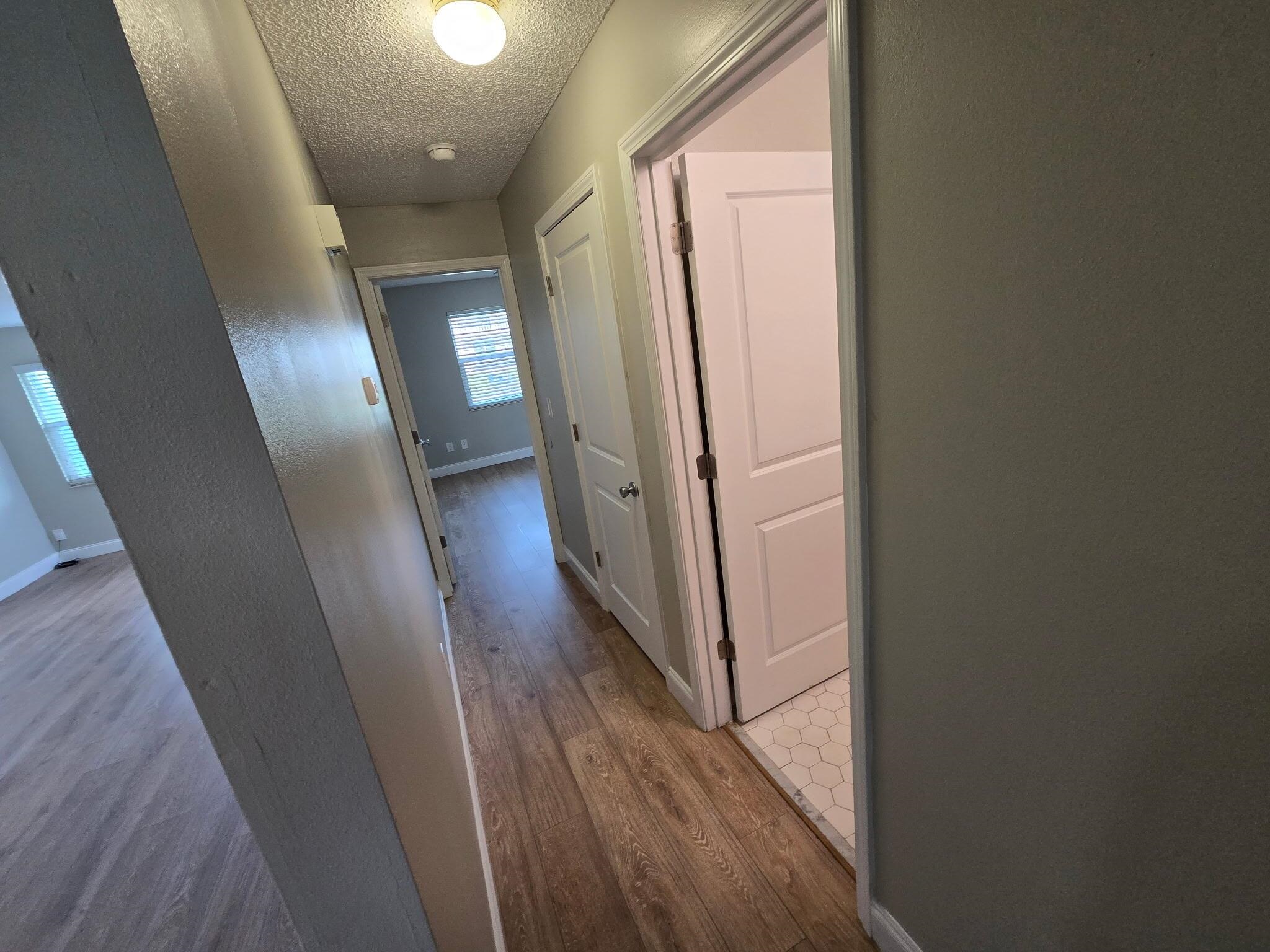 125 Rio Del Mar Street, Unit B St. Augustine, FL 32080 - Photo 9 of 17 Hall featuring a textured ceiling, light wood-type flooring, and a textured wall