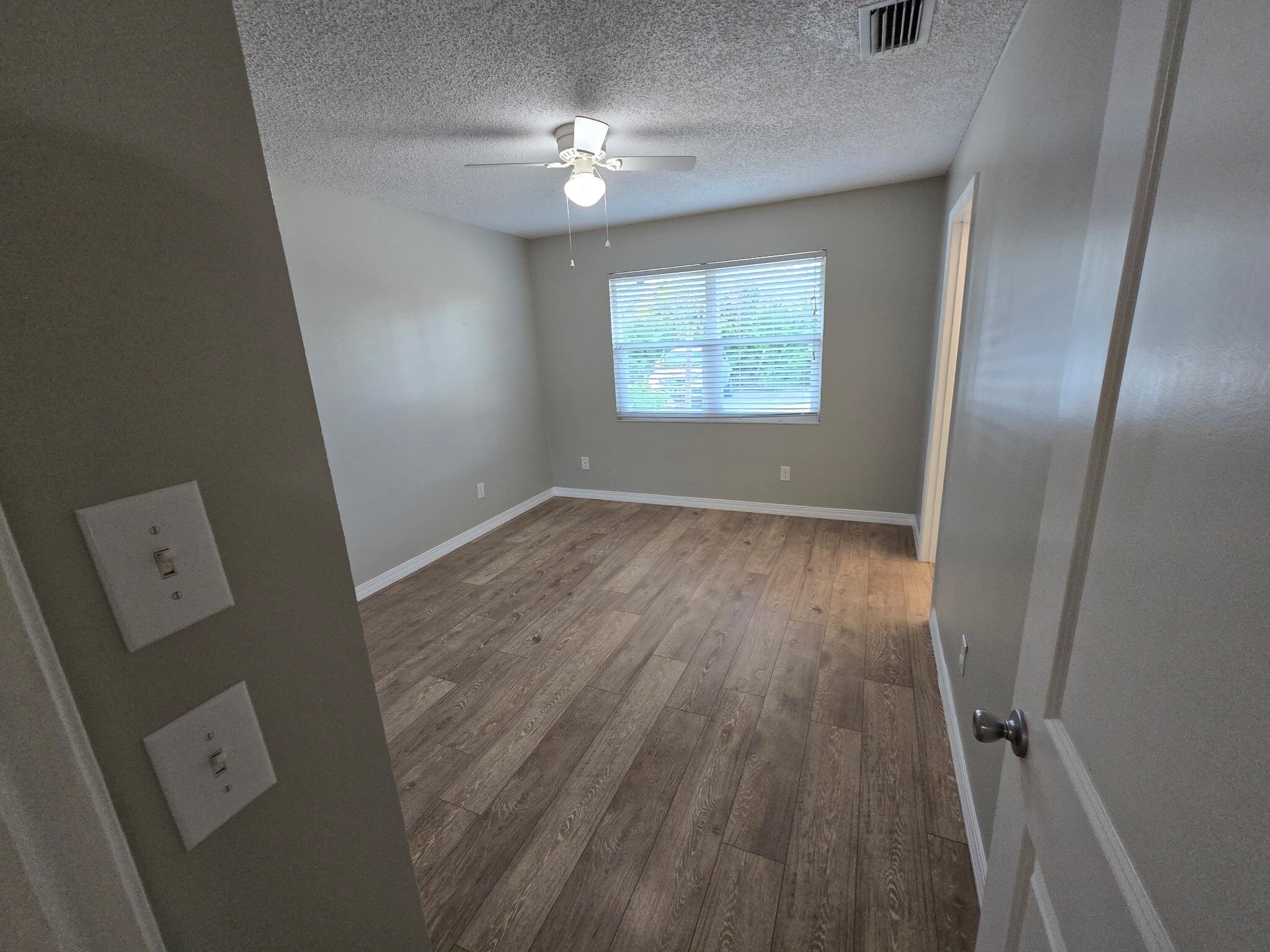 125 Rio Del Mar Street, Unit B St. Augustine, FL 32080 - Photo 10 of 17 Empty room with hardwood / wood-style floors, a textured ceiling, and a ceiling fan