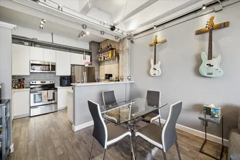 a kitchen with stainless steel appliances kitchen island granite countertop a dining table chairs and white cabinets