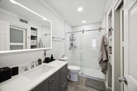 a bathroom with a double vanity sink toilet mirror and shower
