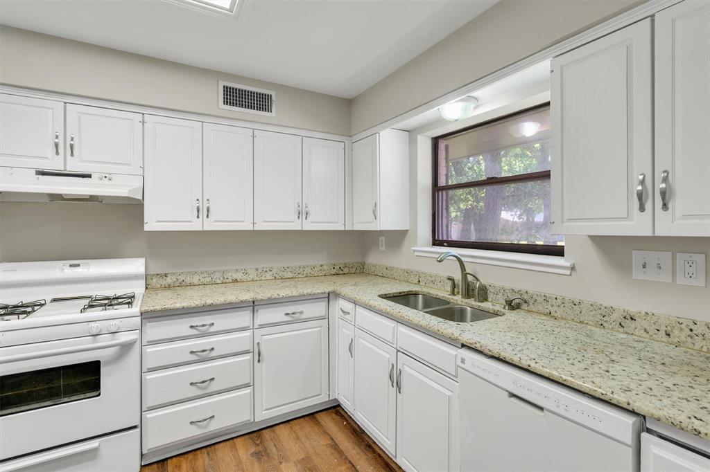 209 Mistletoe Lane Keene, TX 76059 - Photo 16 of 38 a kitchen with granite countertop stainless steel appliances white cabinets granite counter tops and a wooden floors