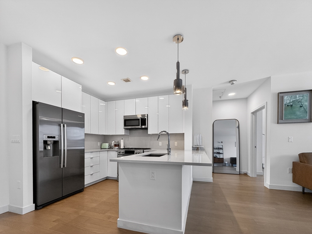 45 Lewis Street, Unit 316 Boston, MA 02128 - Photo 3 of 32 a kitchen with kitchen island a refrigerator a sink a stove a microwave and cabinets