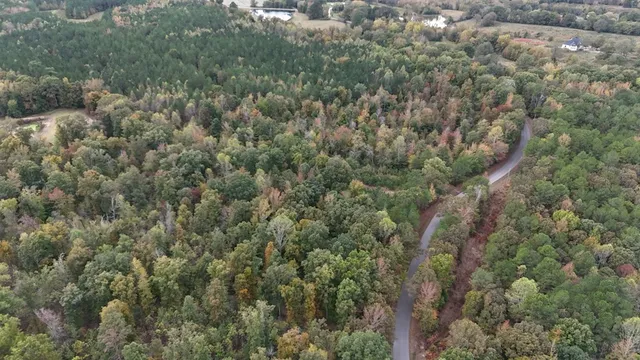 an aerial view of residential house with outdoor space and trees all around