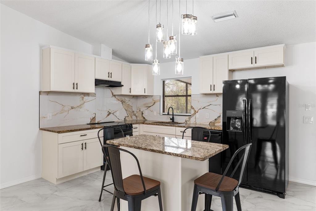 6096 East Tremont Street Inverness, FL 34452 - Photo 14 of 47 a kitchen with kitchen island granite countertop a sink a stove a refrigerator and island with wooden floor