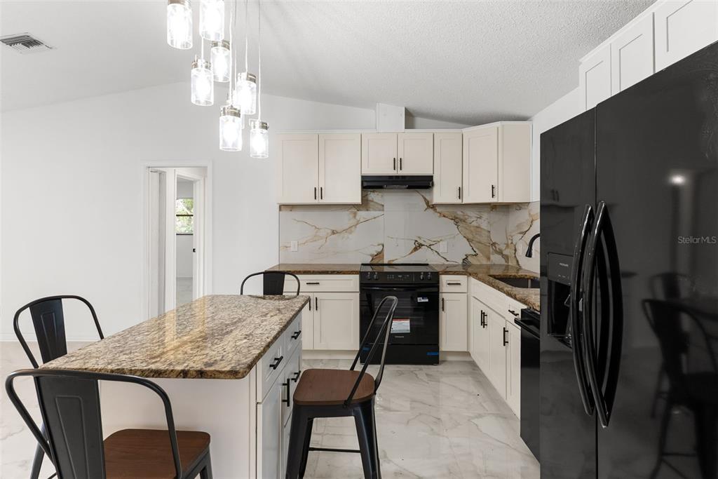 6096 East Tremont Street Inverness, FL 34452 - Photo 16 of 47 a kitchen with granite countertop a stove a sink a refrigerator and cabinets