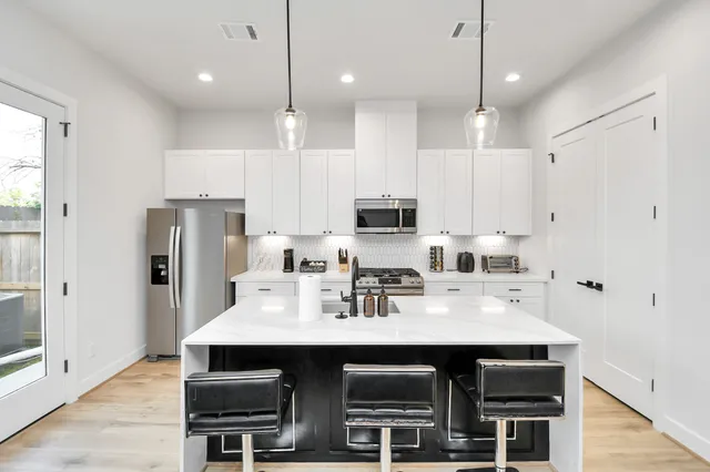 a kitchen with stainless steel appliances a table chairs refrigerator and microwave