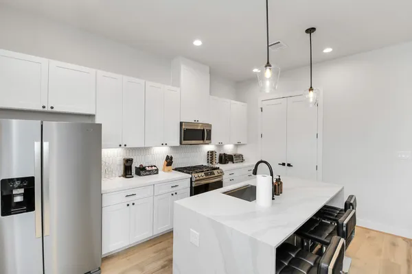 a kitchen with stainless steel appliances a sink a stove a refrigerator a center island and cabinets