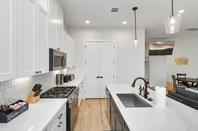 a kitchen that has a sink a stove and a wooden floor
