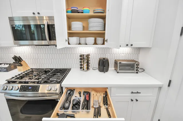 a view of kitchen with a stove a microwave and cabinets