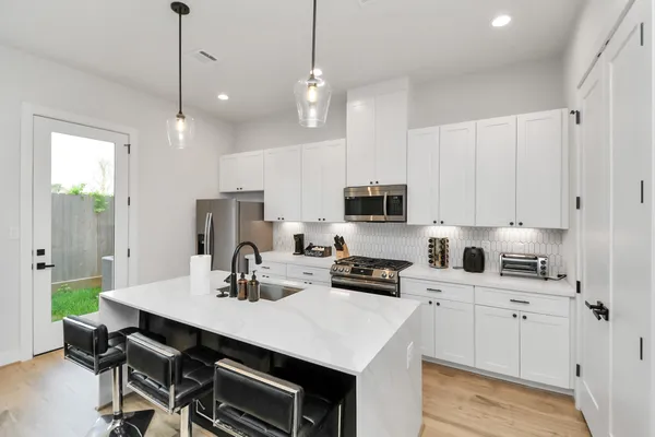 a kitchen with stainless steel appliances a sink a stove a refrigerator a center island and cabinets