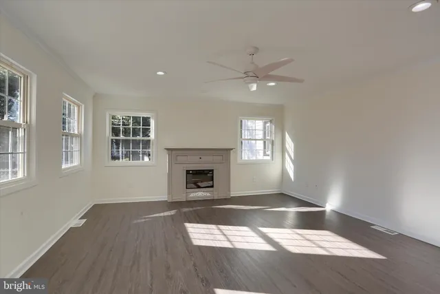 an empty room with windows and fireplace