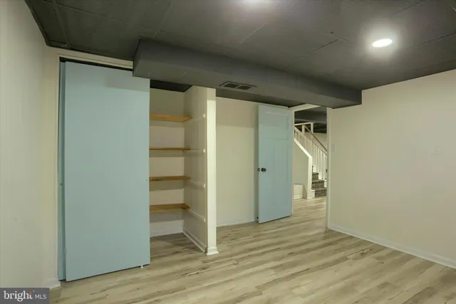 a view of an empty room with wooden floor and closet