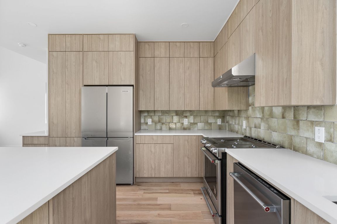 2903 Breeze Terrace, Unit 2 Austin, TX 78722 - Photo 11 of 36 Kitchen featuring stainless steel appliances, light brown cabinets, and exhaust hood