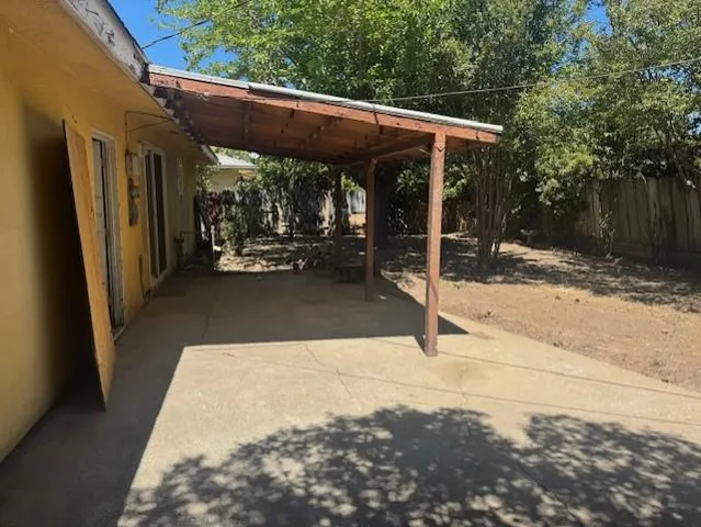 a view of a patio with table and chairs under an umbrella with wooden fence