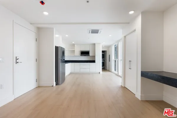 a view of a kitchen with refrigerator and white cabinets