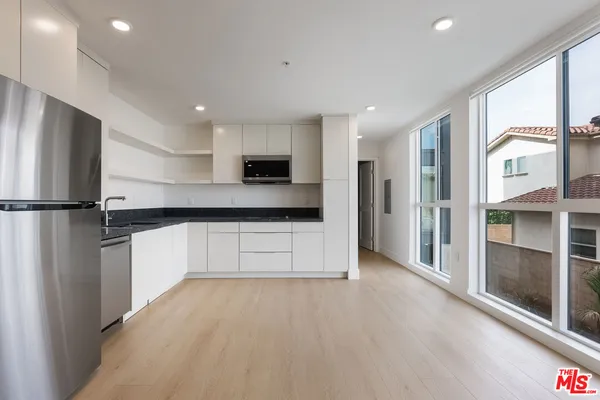 a large kitchen with a refrigerator a stove top oven and a large window with kitchen view