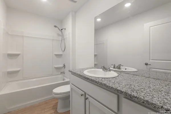 a bathroom with a granite countertop sink a toilet and shower