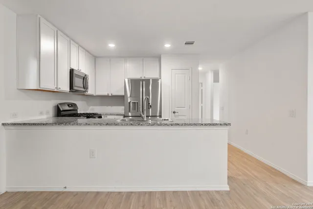 a view of kitchen with stainless steel appliances granite countertop cabinets and wooden floor