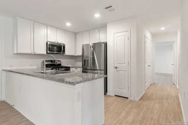 a kitchen with stainless steel appliances granite countertop a refrigerator microwave and sink