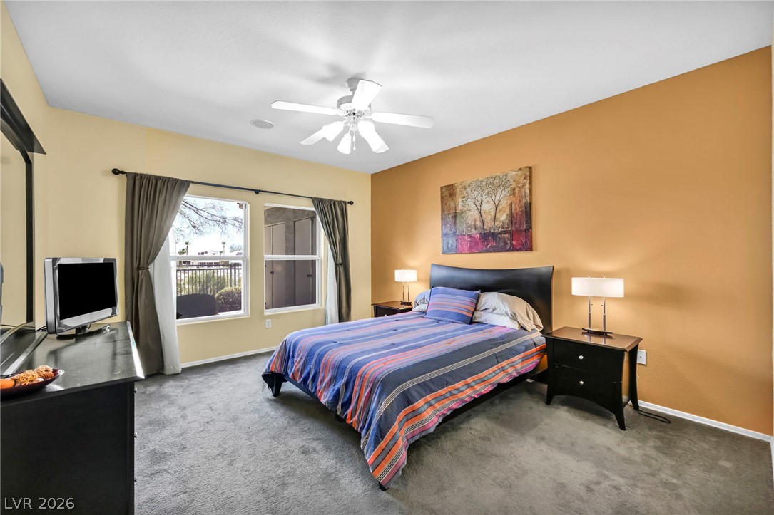 10730 Amber Ridge Drive, Unit 101 Las Vegas, NV 89144 - Photo 19 of 32 Plush carpeting and a ceiling fan create a comfortable atmosphere in this well-appointed bedroom.
