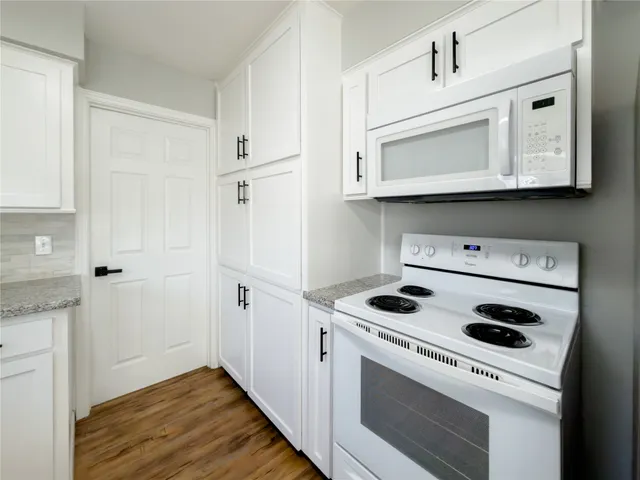 a kitchen with white cabinets and white appliances