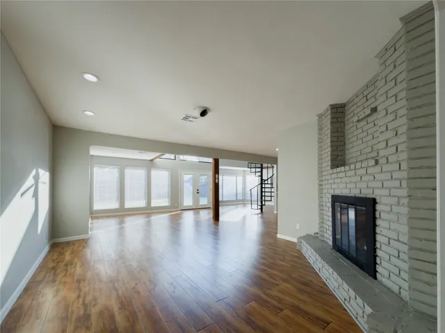 a view of an empty room with wooden floor and a fireplace