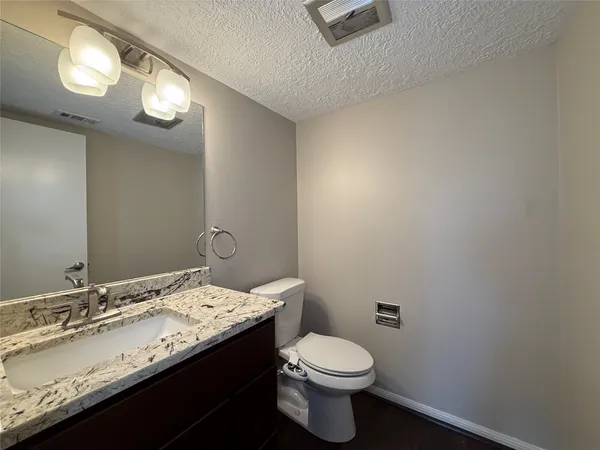 a bathroom with a granite countertop sink a toilet and a mirror