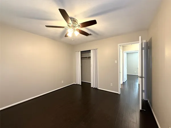 an empty room with wooden floor closet and windows