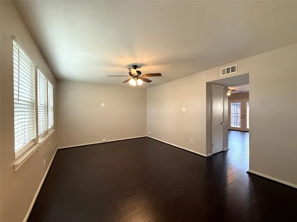 a view of an empty room with wooden floor and a window