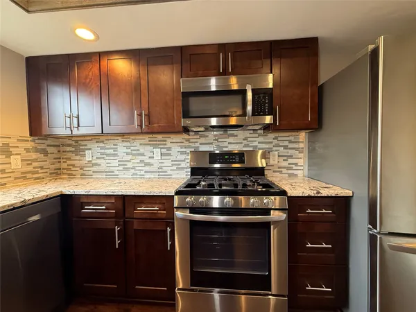 a kitchen with stainless steel appliances wooden cabinets and a stove top oven