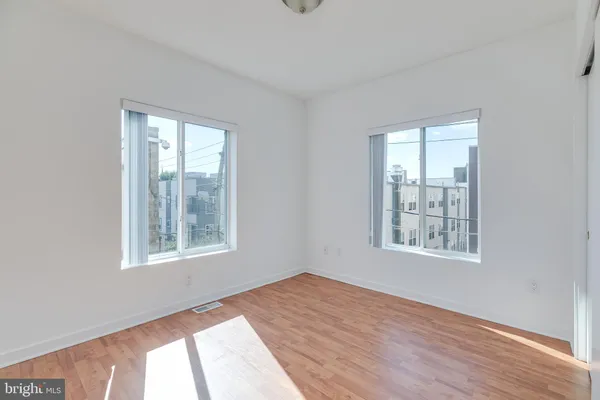 an empty room with wooden floor and windows