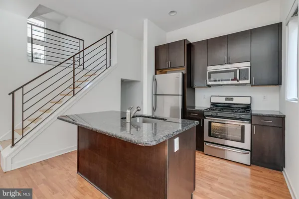 a kitchen with kitchen island granite countertop a sink and stainless steel appliances