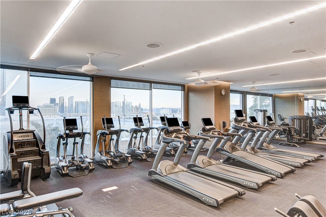 4381 West Flamingo Road, Unit 3002 Las Vegas, NV 89103 - Photo 7 of 59 A well-equipped fitness center showcases wall-to-wall windows framing panoramic city skyline views.
