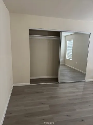 a view of an empty room with wooden floor and closet