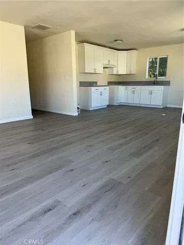 a kitchen with granite countertop wooden cabinets and wooden floor
