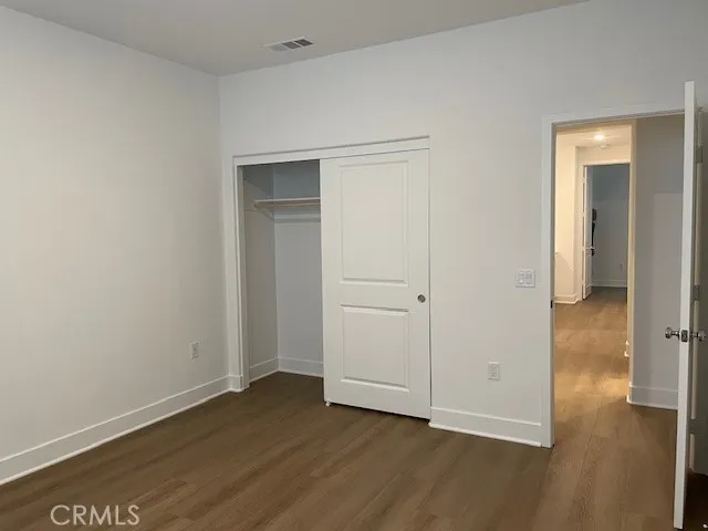 an empty room with wooden floor & closet area