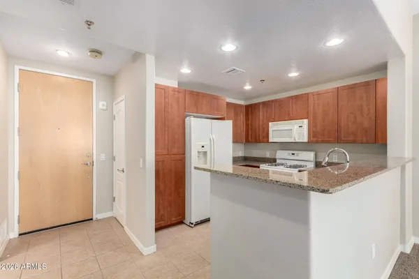 a view of kitchen with stainless steel appliances granite countertop a refrigerator and a stove top oven