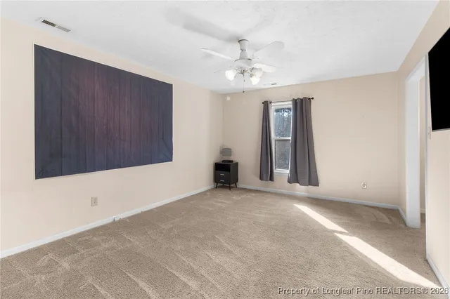 a view of an empty room with chandelier fan