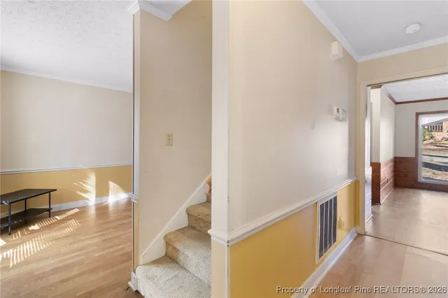 a view of a hallway with wooden floor and dining room