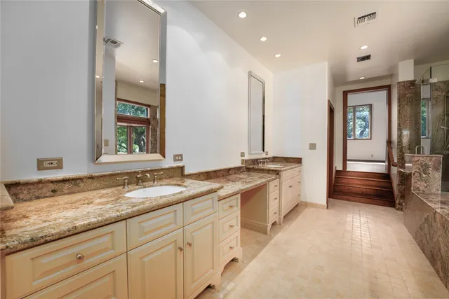 a bathroom with a granite countertop sink a mirror and shower