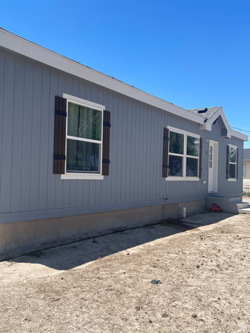 289 West Center Street Hinckley, UT 84635 - Photo 10 of 13 Light gray siding exterior with white window trim and dark wood-tone shutters