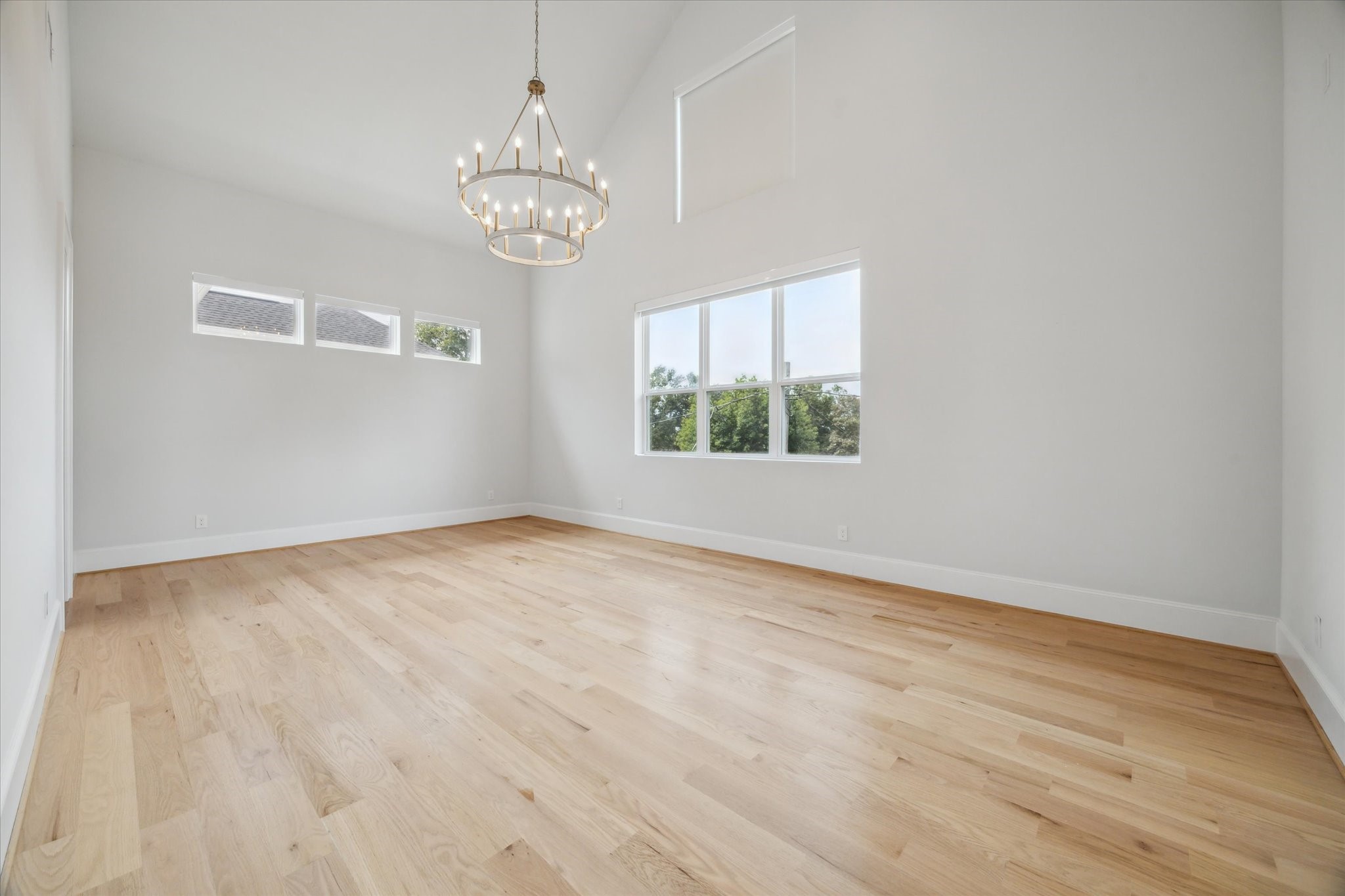 2202 Hewitt Drive Houston, TX 77018 - Photo 21 of 39 The primary suite features hardwood flooring, large windows with remote-controlled automated shades, and a vaulted ceiling reaching 20 feet, complemented by recessed lighting and an updated chandelier.