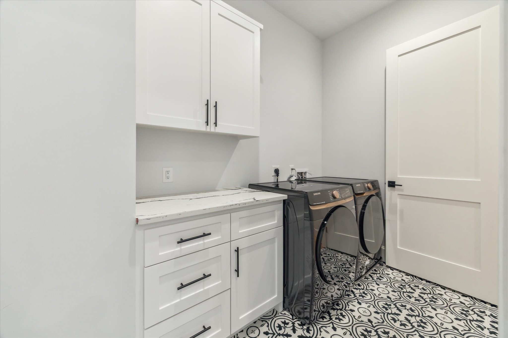 2202 Hewitt Drive Houston, TX 77018 - Photo 27 of 39 The utility room is accessible from both the hallway and the primary closet. It features a Samsung Smart washer and dryer, stylish tile flooring, and quartz countertops with built-in upper and lower cabinets for ample storage.